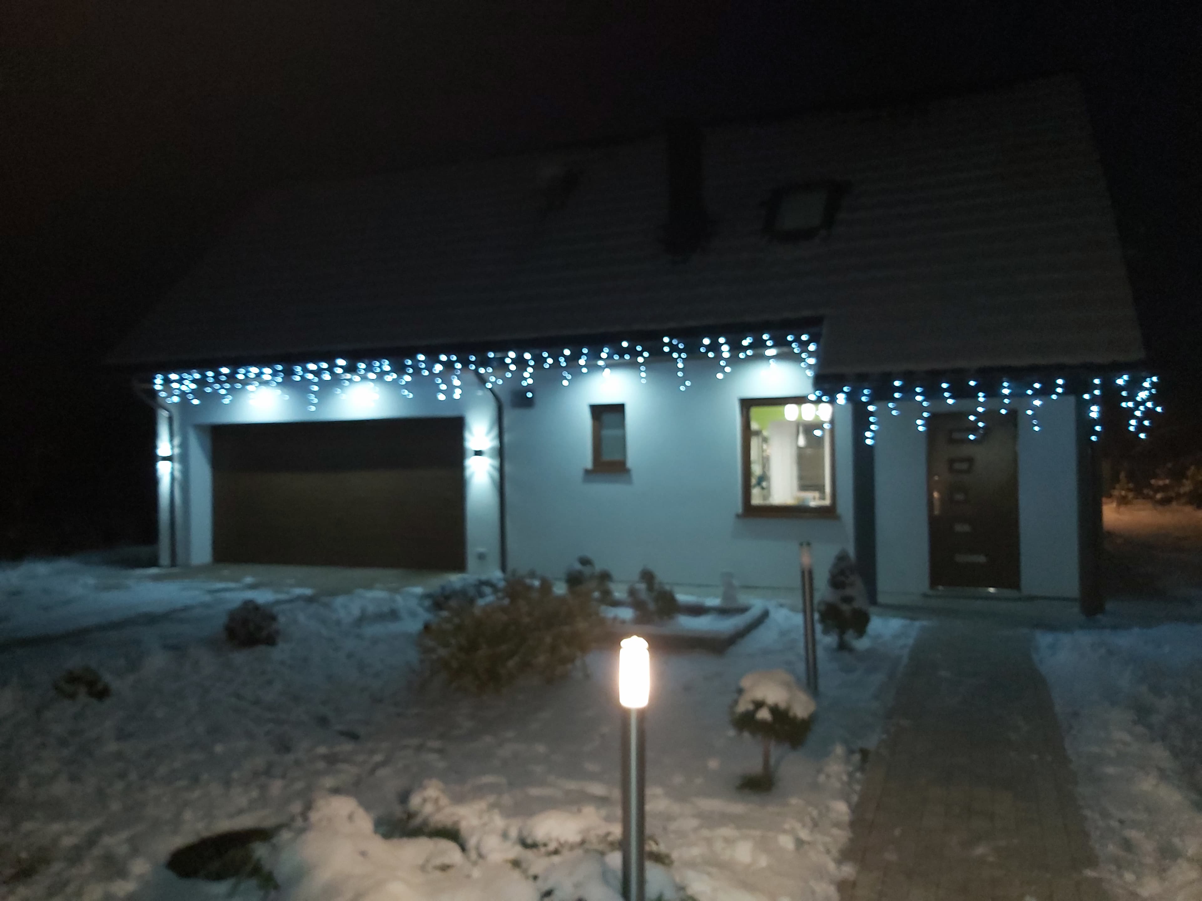 Wejście do domku i garaż w nocy, oświetlone